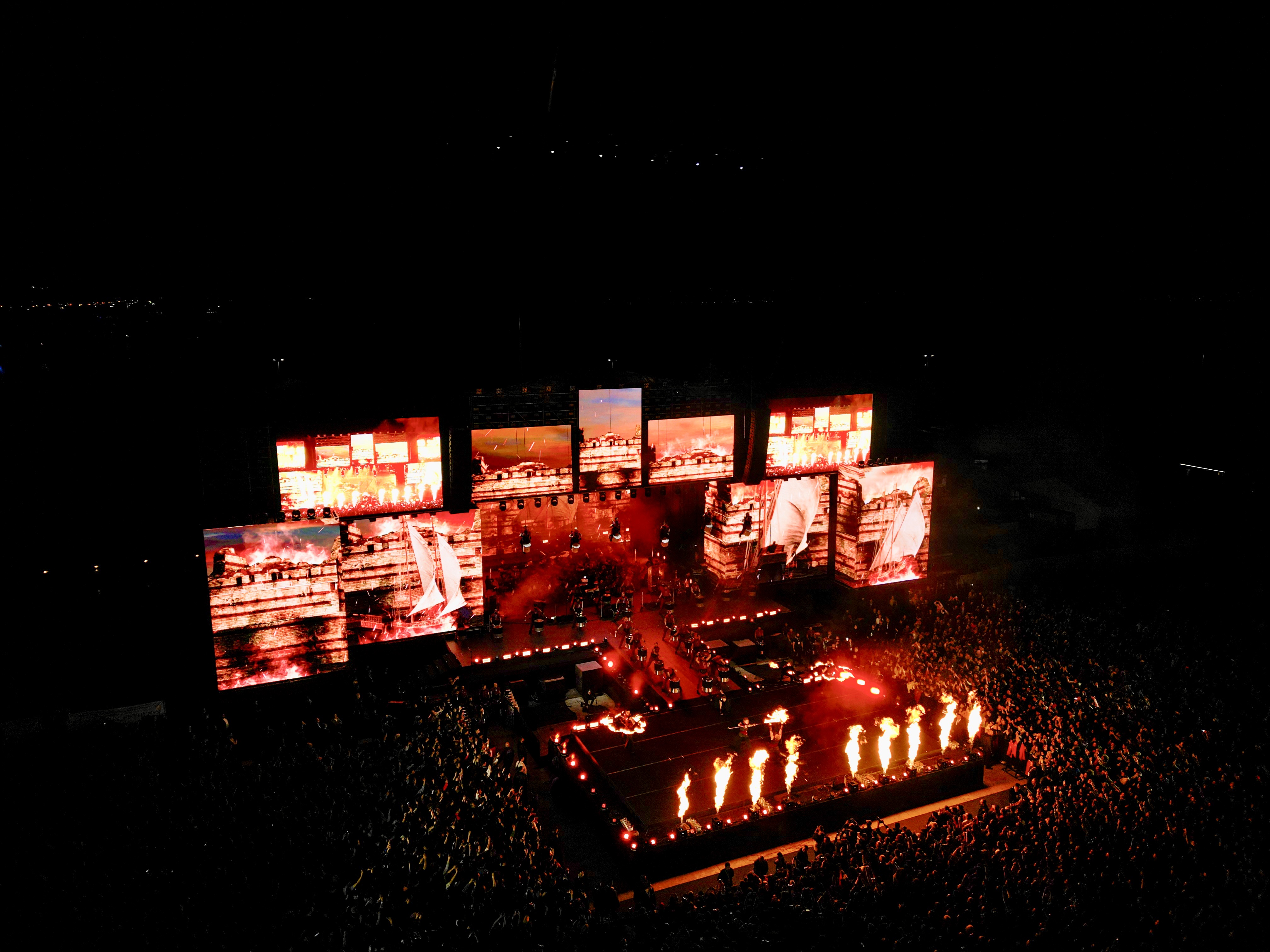 Drummers in LED costumes are rapidly hoisted high above by speed winches. 